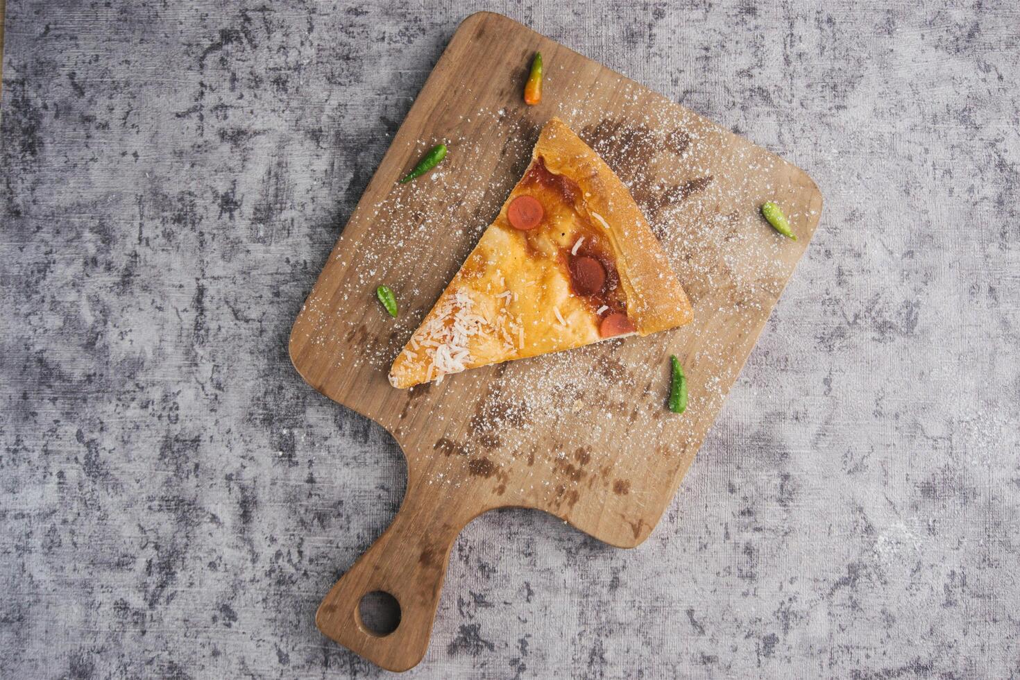 Last slice of pizza left on wooden cutting board photo