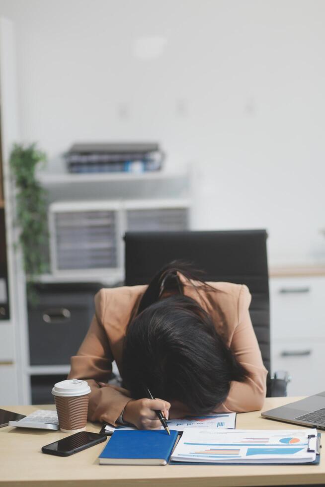 Portrait of tired young business Asian woman work with documents tax laptop computer in office. Sad, unhappy, Worried, Depression, or employee life stress concept photo