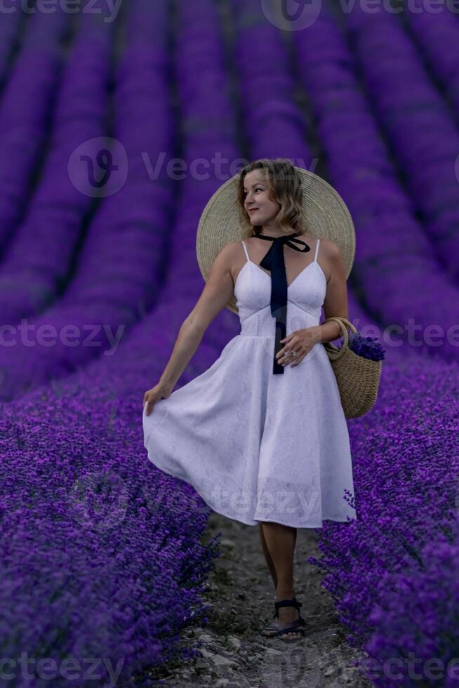 A woman in a white dress stands in a field of purple flowers photo