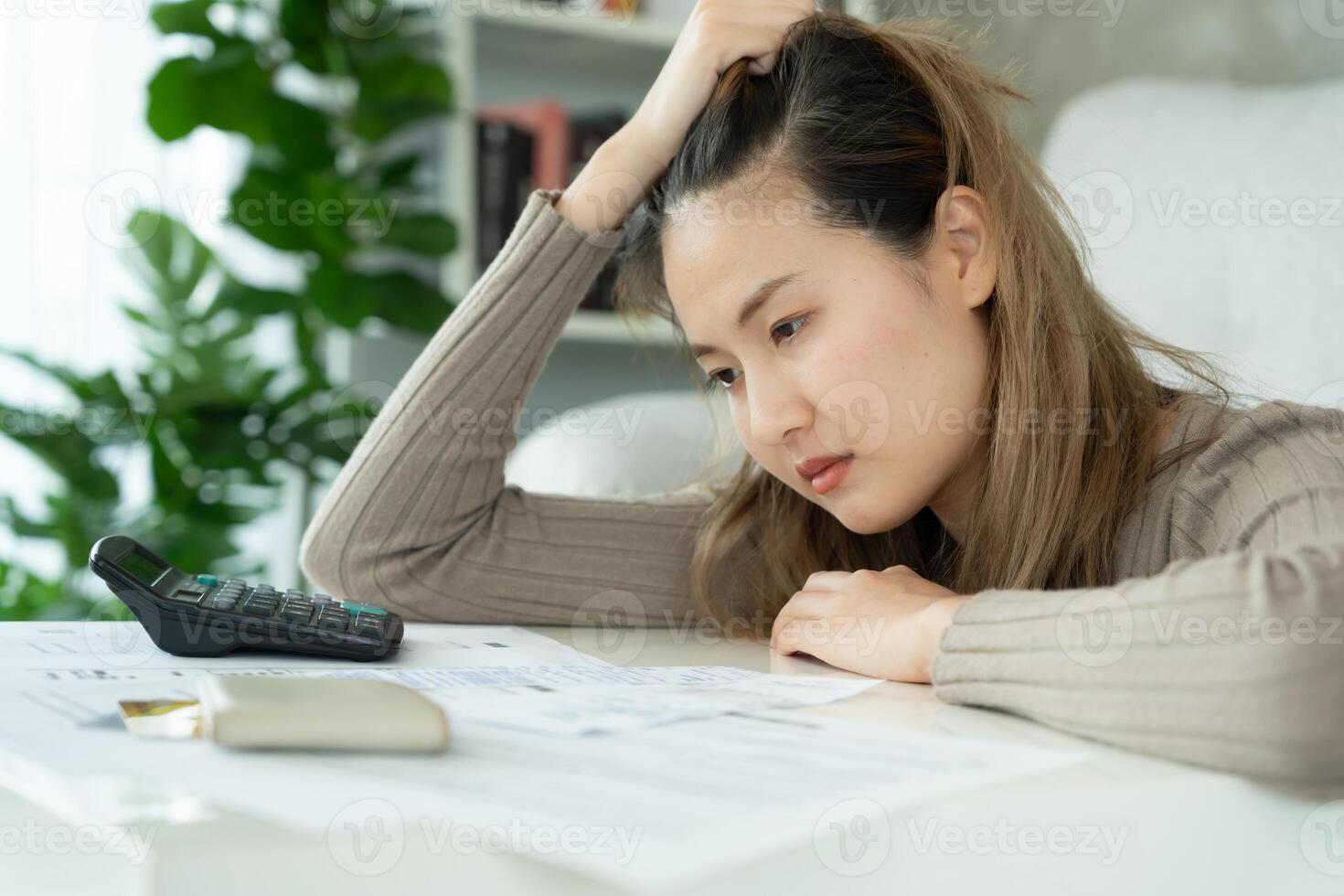 Stressed and headache asian woman with large bills or invoices no money to pay to expenses and credit card debt. shortage, Financial problems, mortgage, loan, bankruptcy, bankrupt, poor, empty wallet photo
