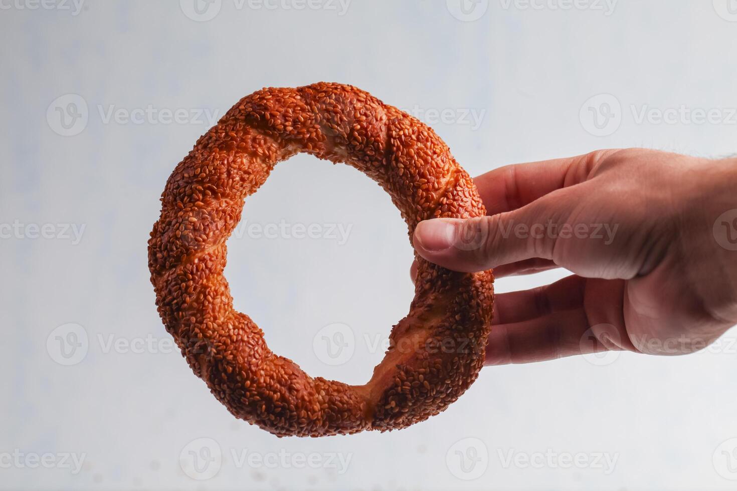 Delicious sesame bread ring held by a hand in clear background photo