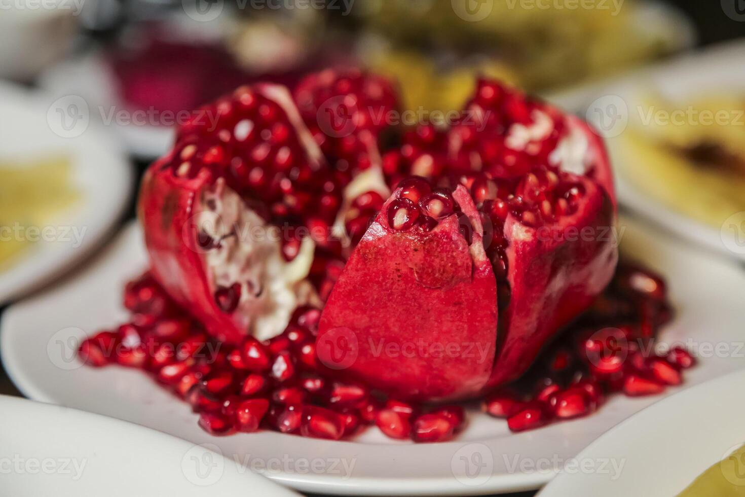 Freshly cut pomegranate with vibrant seeds on a white plate photo