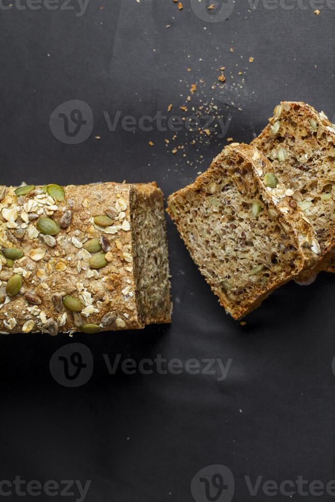 Freshly baked whole grain bread with seeds on a dark background photo