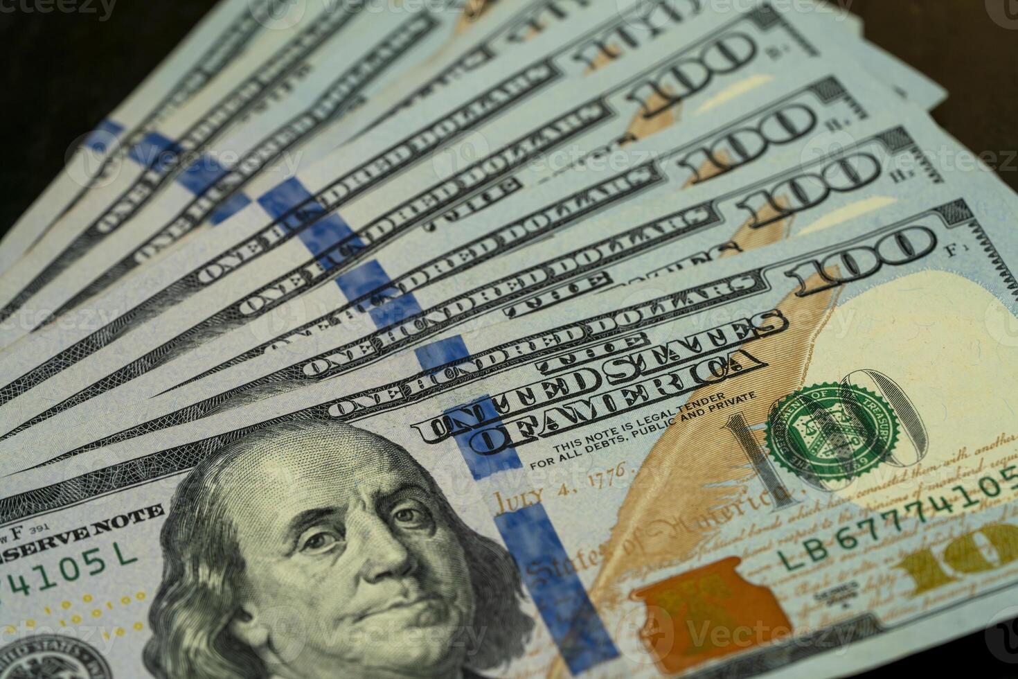 Stacks of hundred dollar bills arranged on a wooden surface photo