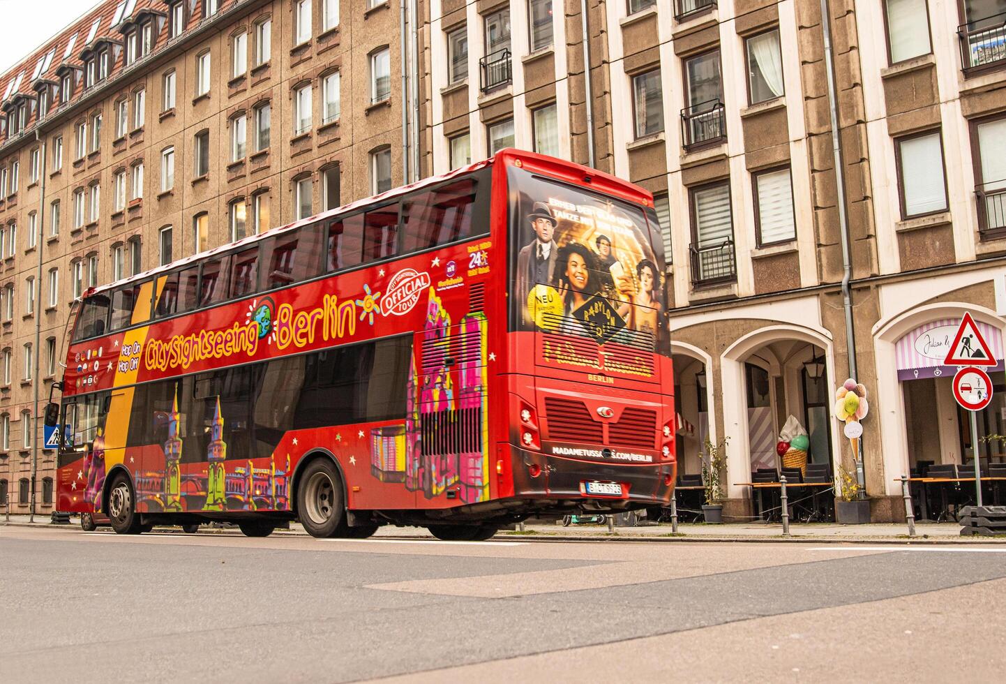 Berlin, Germany, January 5th, 2024. Vibrant red hop-on hop-off bus with Berlin landmarks illustrations, riding in the historical city center, offering sightseeing tours, exploring popular attractions photo