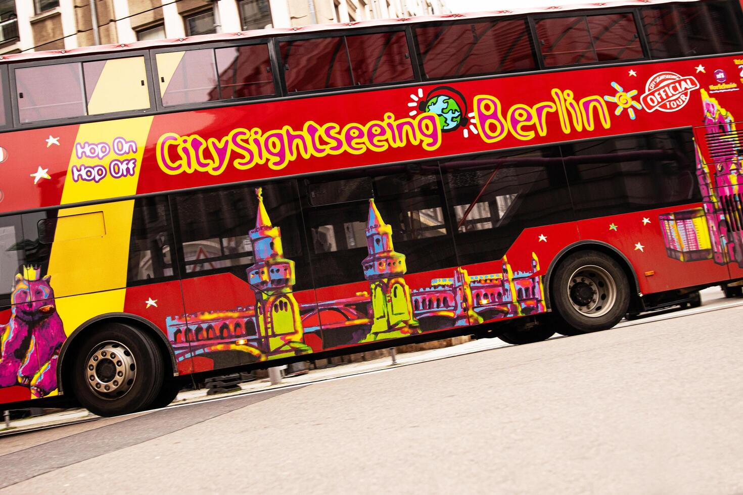 Berlin, Germany, January 5th, 2024. Vibrant red hop-on hop-off bus with Berlin landmarks illustrations, riding in the historical city center, offering sightseeing tours, exploring popular attractions photo
