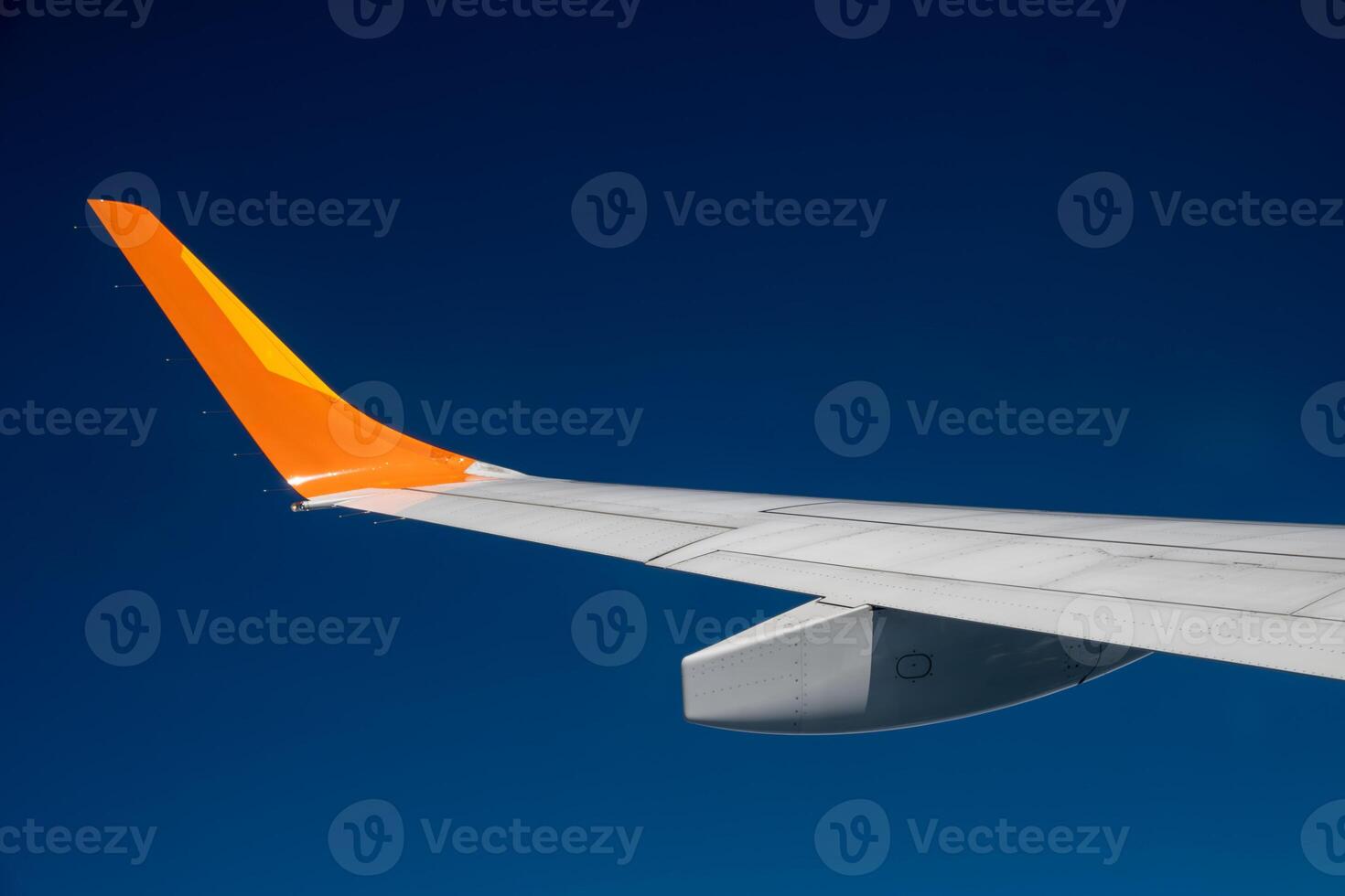 A plane wing extends against a deep blue sky. Travel concept photo