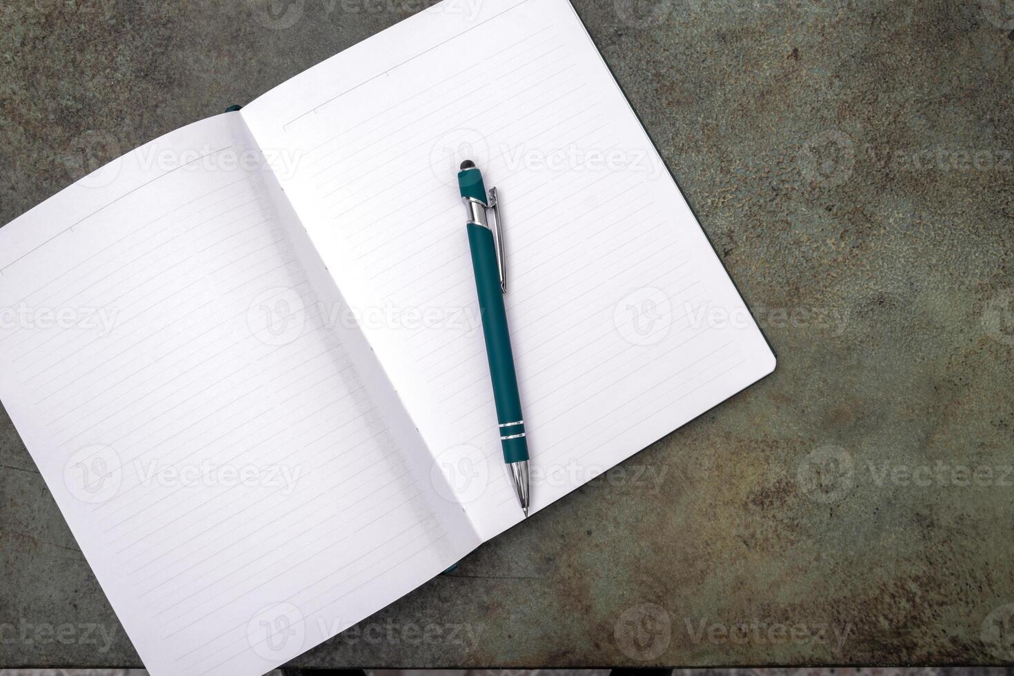An open notebook with a pen lies on a dark textured surface. photo