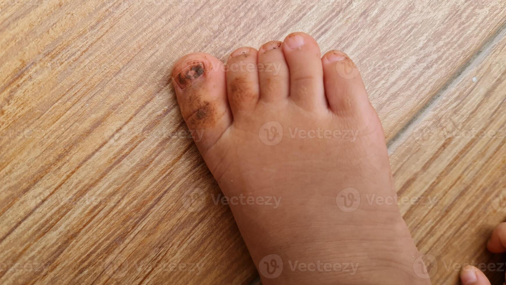 Close-up of a Child's Dirty Foot on a Wooden Floor photo