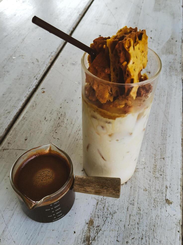 Cold milk with melted toffee sugar in a glass served with strong black coffee on white wooden table photo