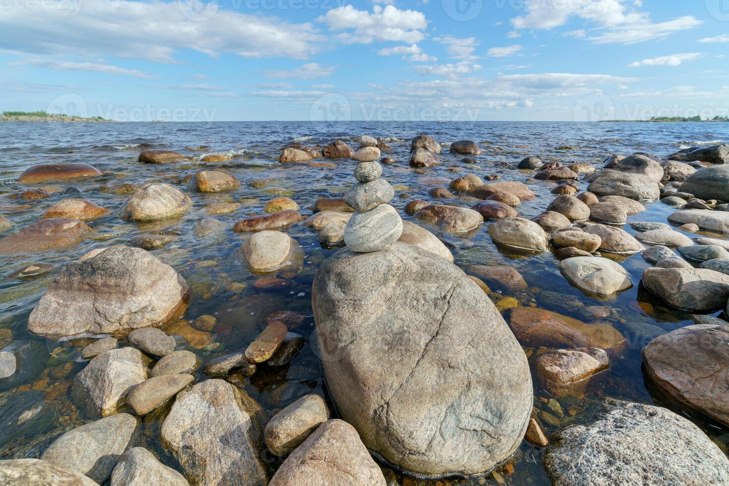 Rocky lakeside. In the center is a pyramid of stones. photo