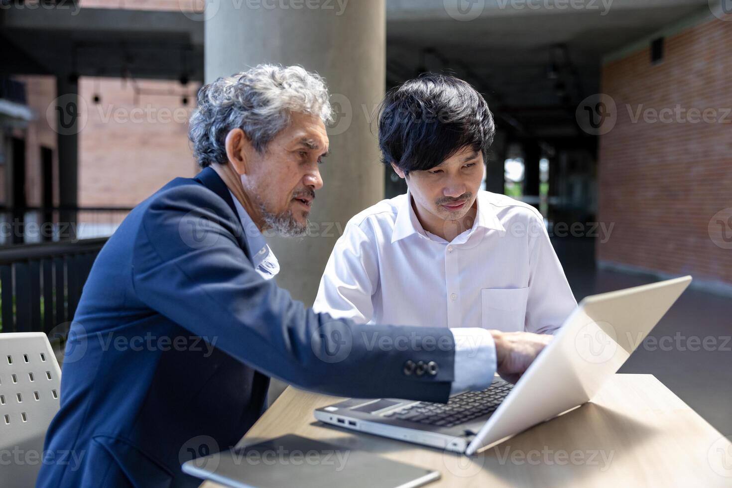 Asian senior professor is giving advice to the college student on his research thesis while sitting in the university faculty for education, academic and business photo