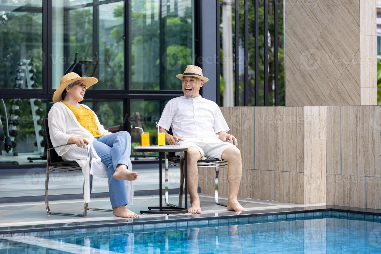 Senior Asian couple get refreshment fruit juice by the swimming pool in the tropical resort hotel for summer vacation travel and happy retirement elder for healthy aging activity wellness concept photo