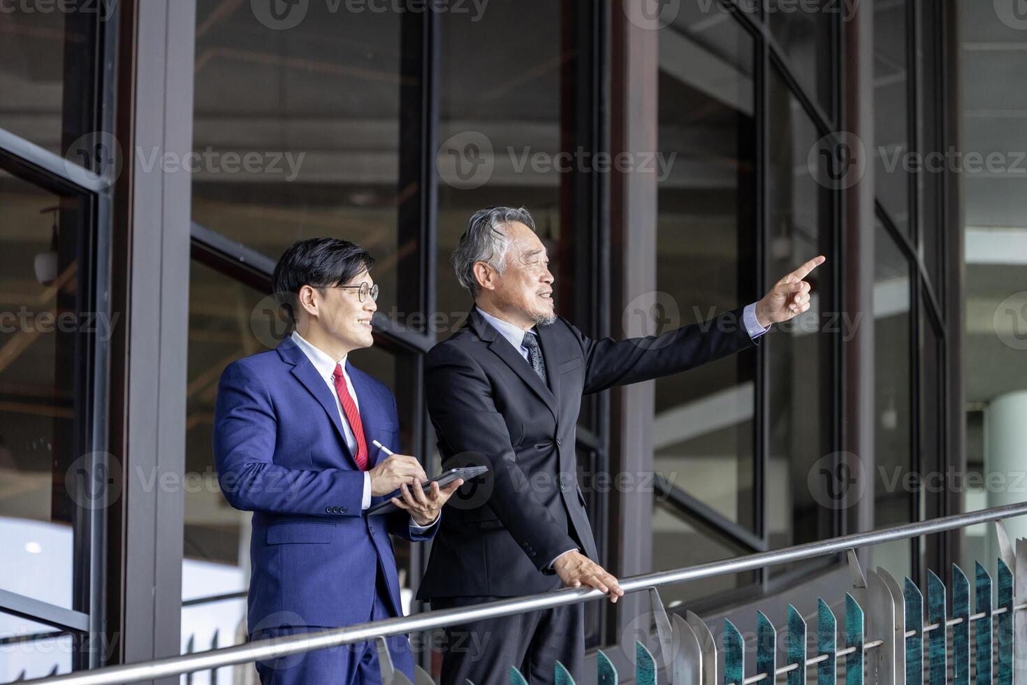 Asian senior businessman giving advice to the new manager while working inside modern style office photo