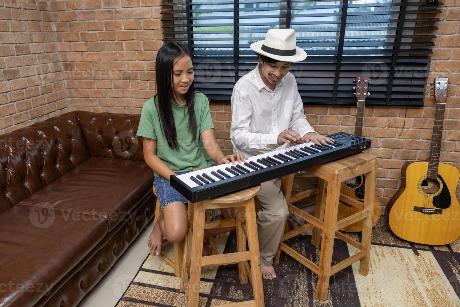 Young asian girl is learning how to play keyboard from her teacher in the after school music class for education children skill and talent development concept photo