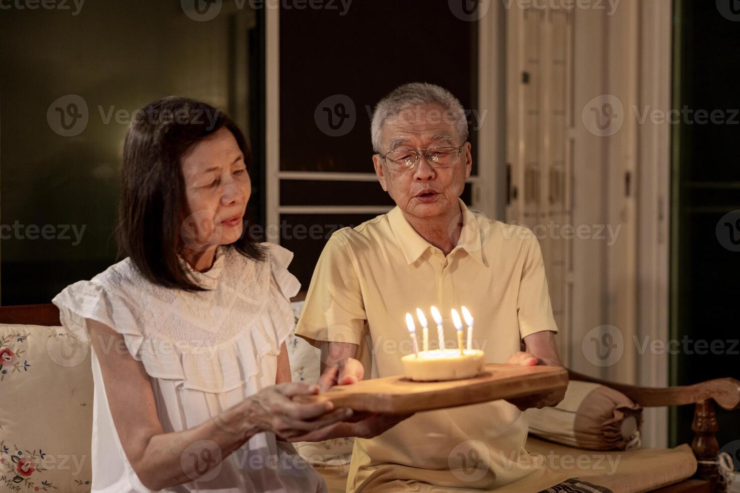 Senior asian couple is happily celebrating birthday together at home for love, relationship, bonding, longevity and marriage concept photo