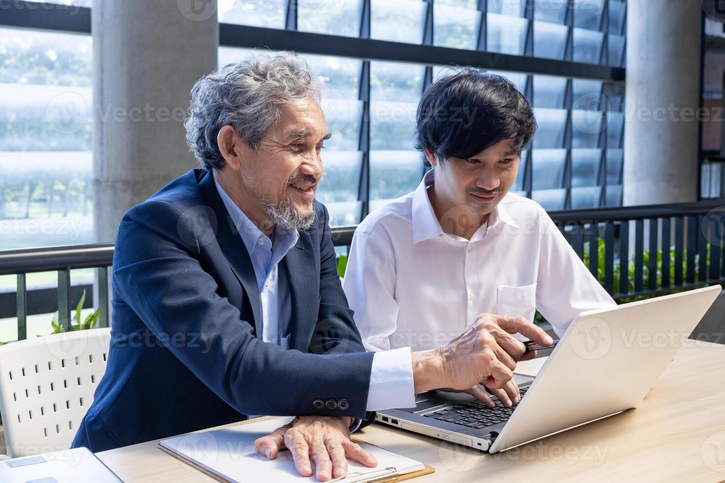 Asian senior professor is giving advice to new college student on the research thesis while sitting in the university faculty for education, academic and business photo