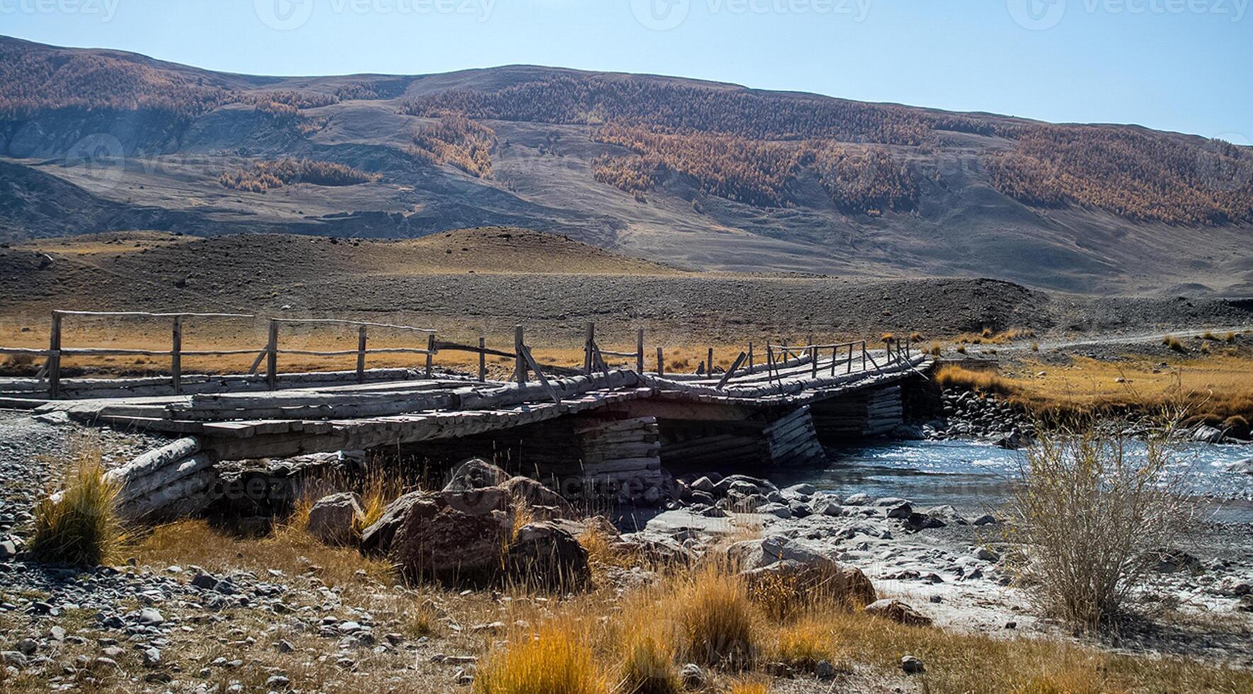 An old wooden bridge over a mountain river in Altai. photo