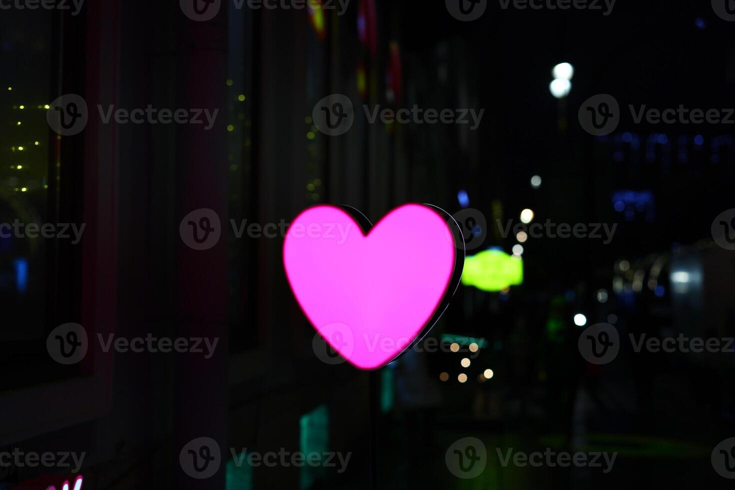 A Vibrant Neon Pink Heart Set Against a Stunning Urban Nightscape Full of Charm and Life photo