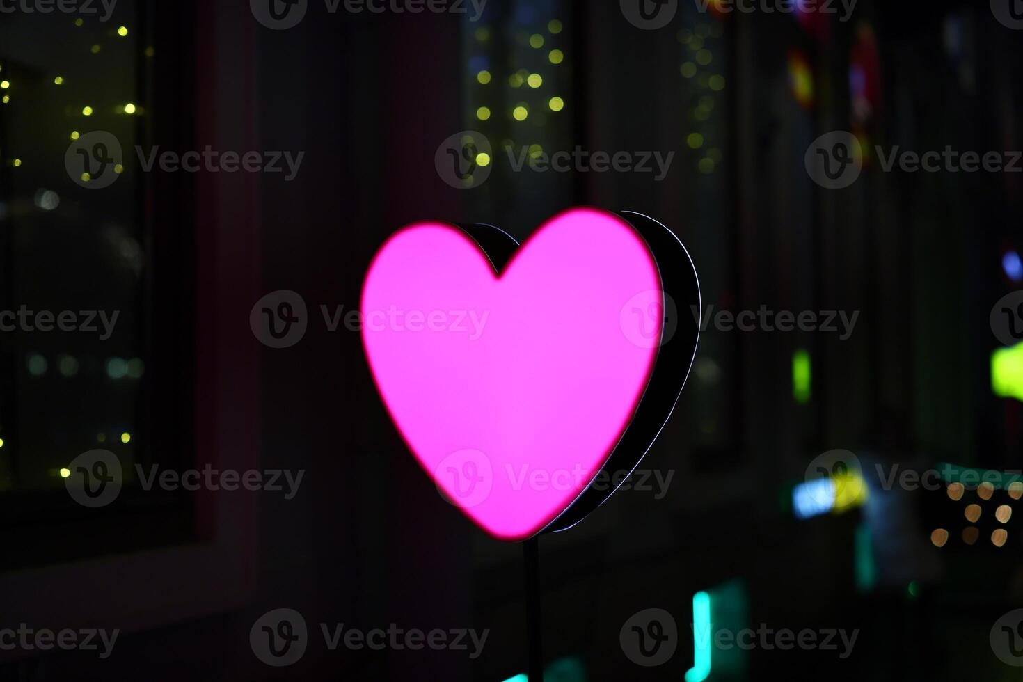 A Vibrant Pink Heart Neon Sign Residing in a Lively Urban Setting That Captivates All photo