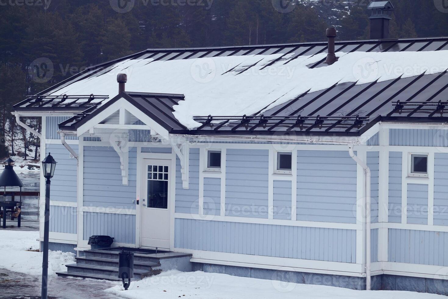 Charming Blue House Set in a Snowy Winter Landscape, creating a calming atmosphere photo