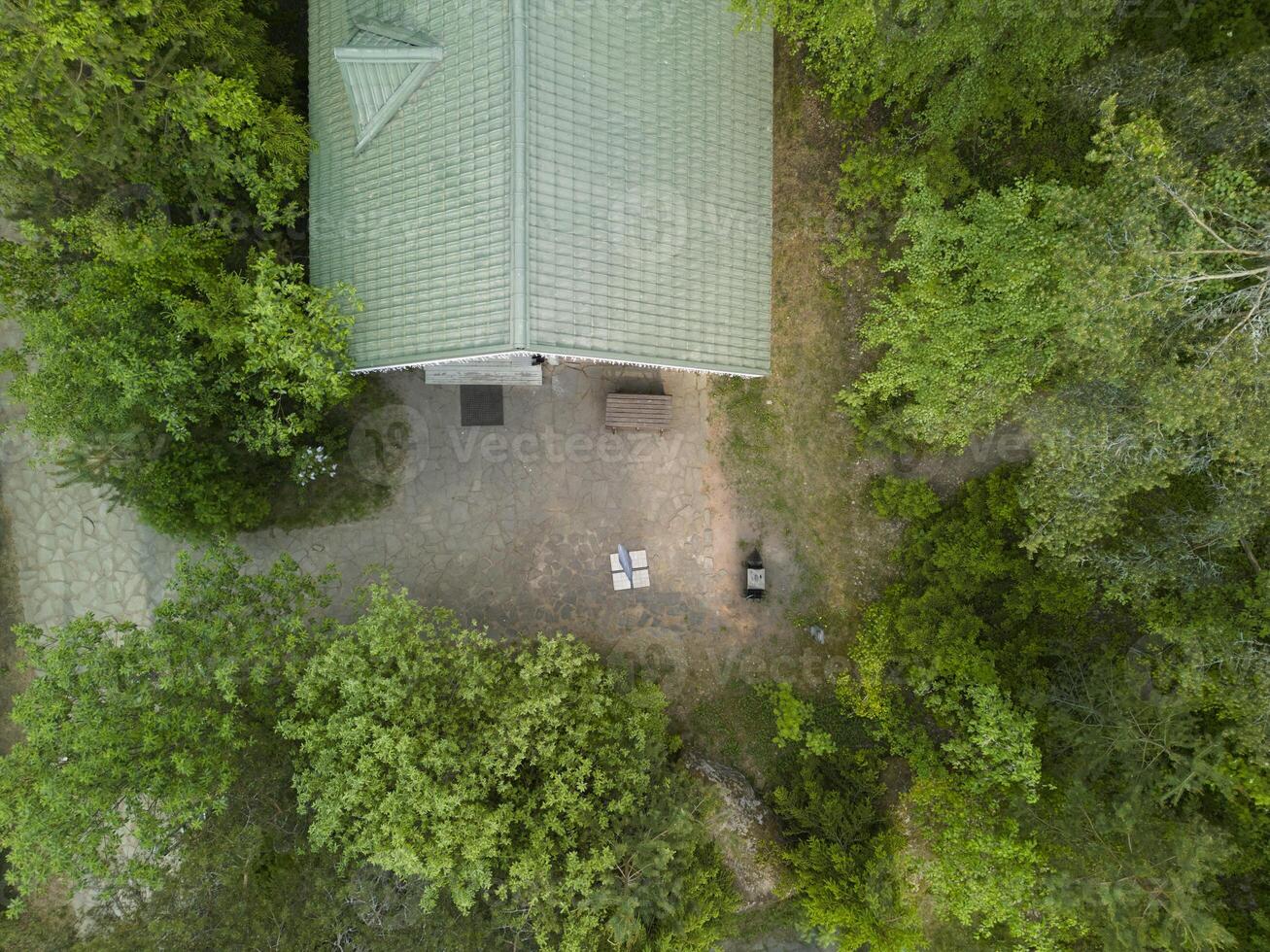 A beautiful aerial view showcases a charming house that is completely surrounded by lush greenery photo