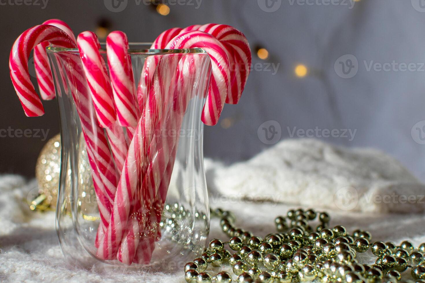 Red and white caramel canes in a glass against the background of lights photo