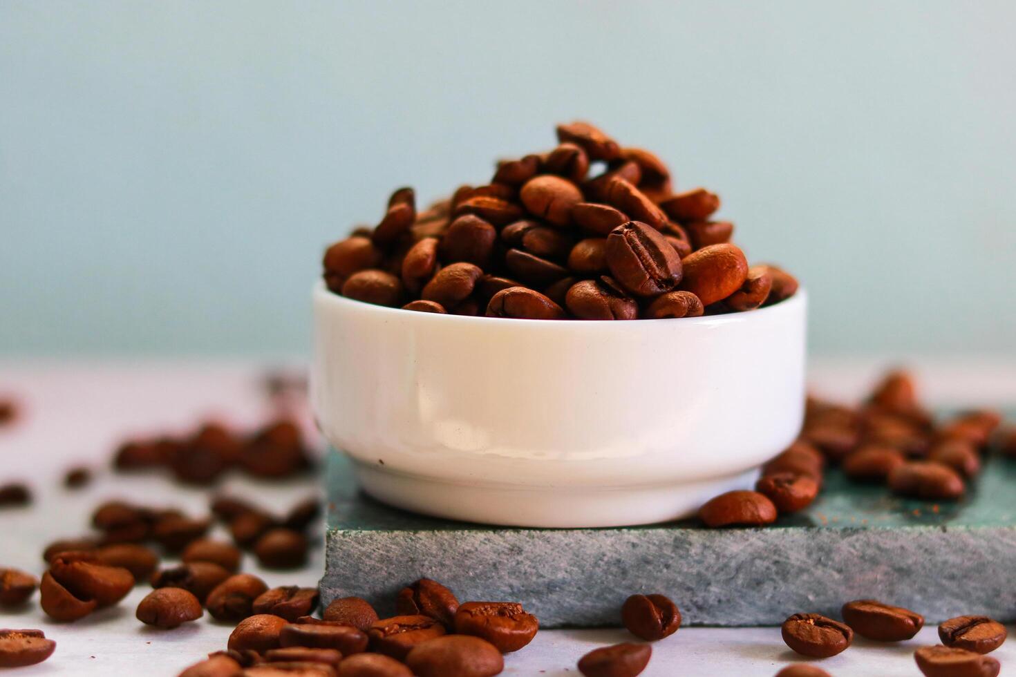 Coffee beans in a white bowl on a turquoise background photo