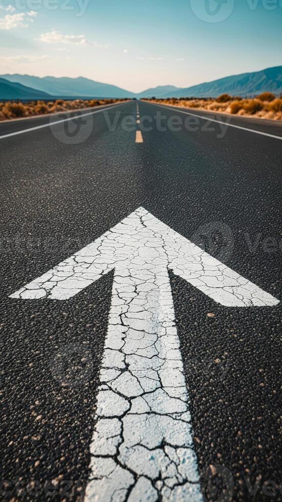 Cracked road leading forward through a desert landscape with mountains in the background during the day photo