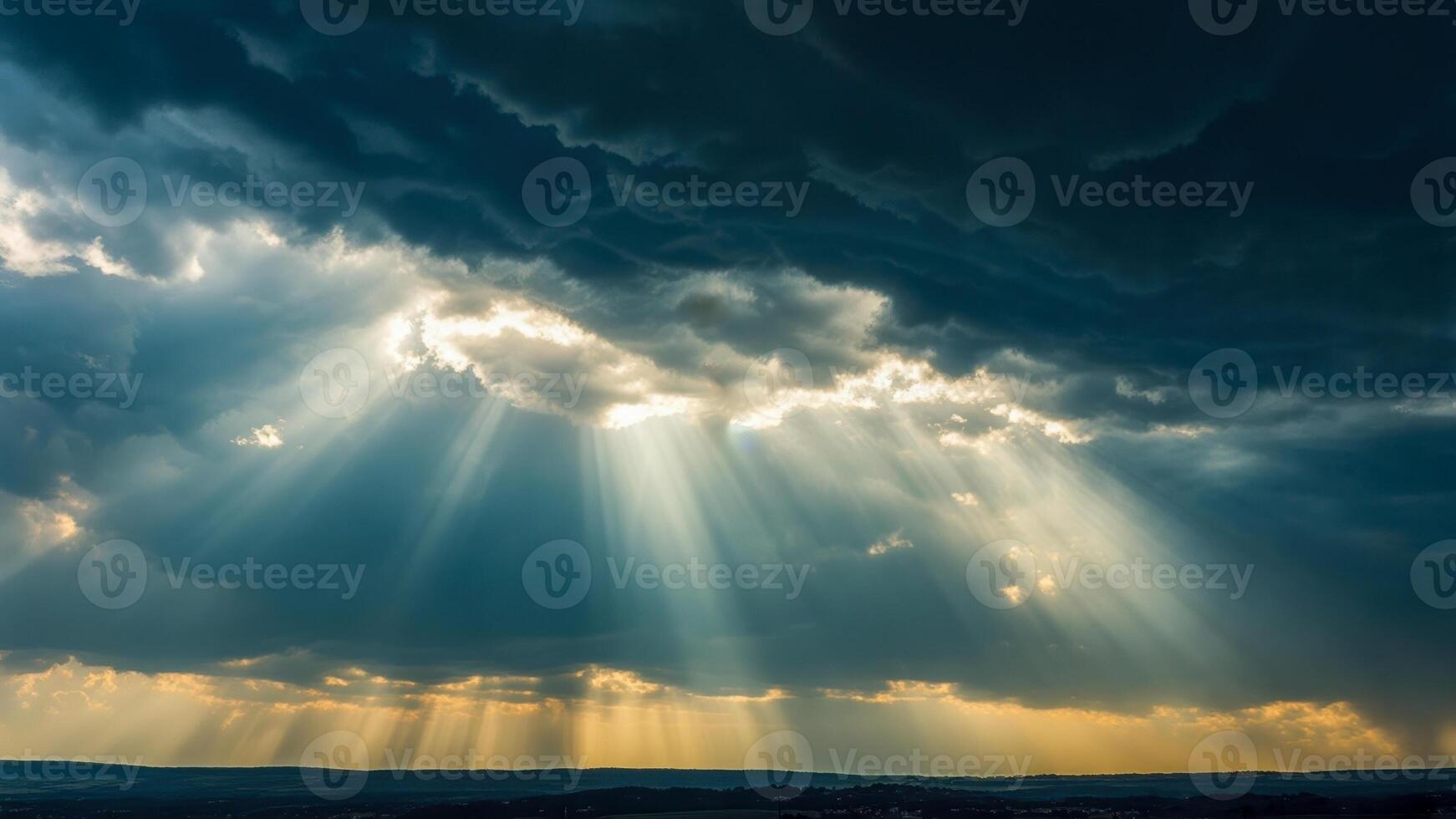 Beautiful sun rays breaking through dark clouds over a serene landscape at dusk photo