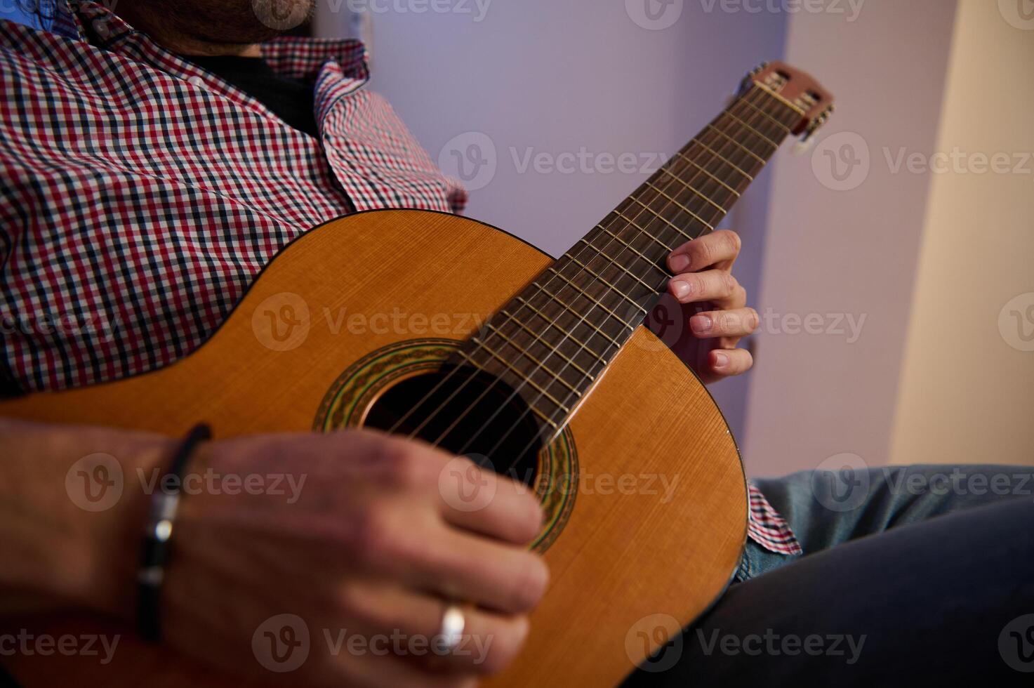 Man strumming a classical guitar in a casual indoor setting photo