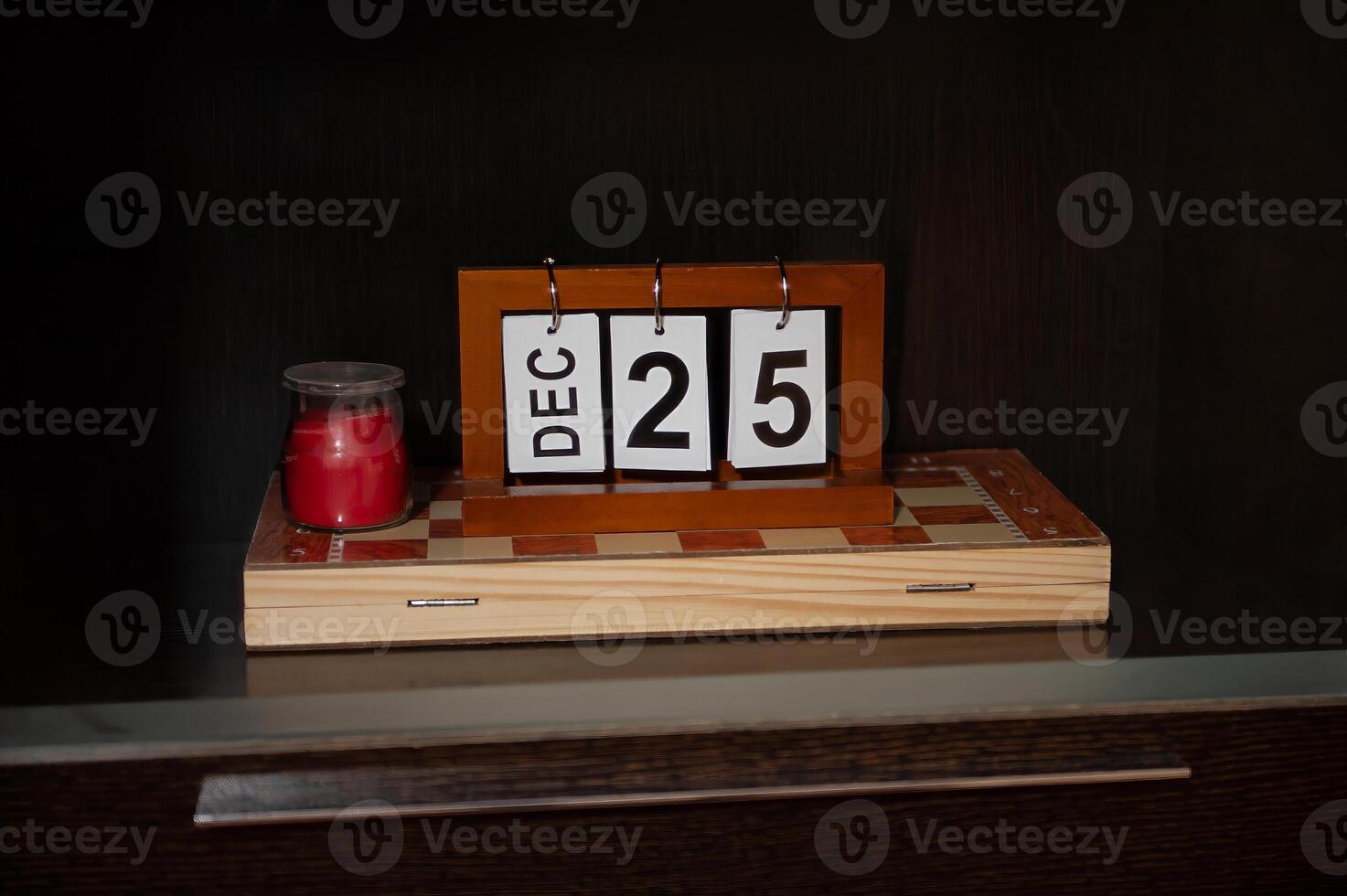 Wooden block calendar with December 25th displayed next to red candle photo