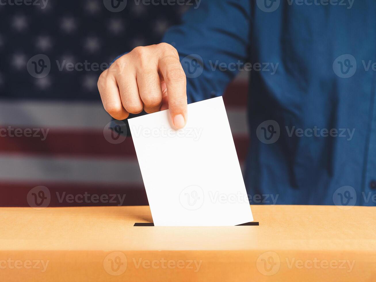 Hand voter holding ballot paper putting into the voting box at place election with an American flag background photo