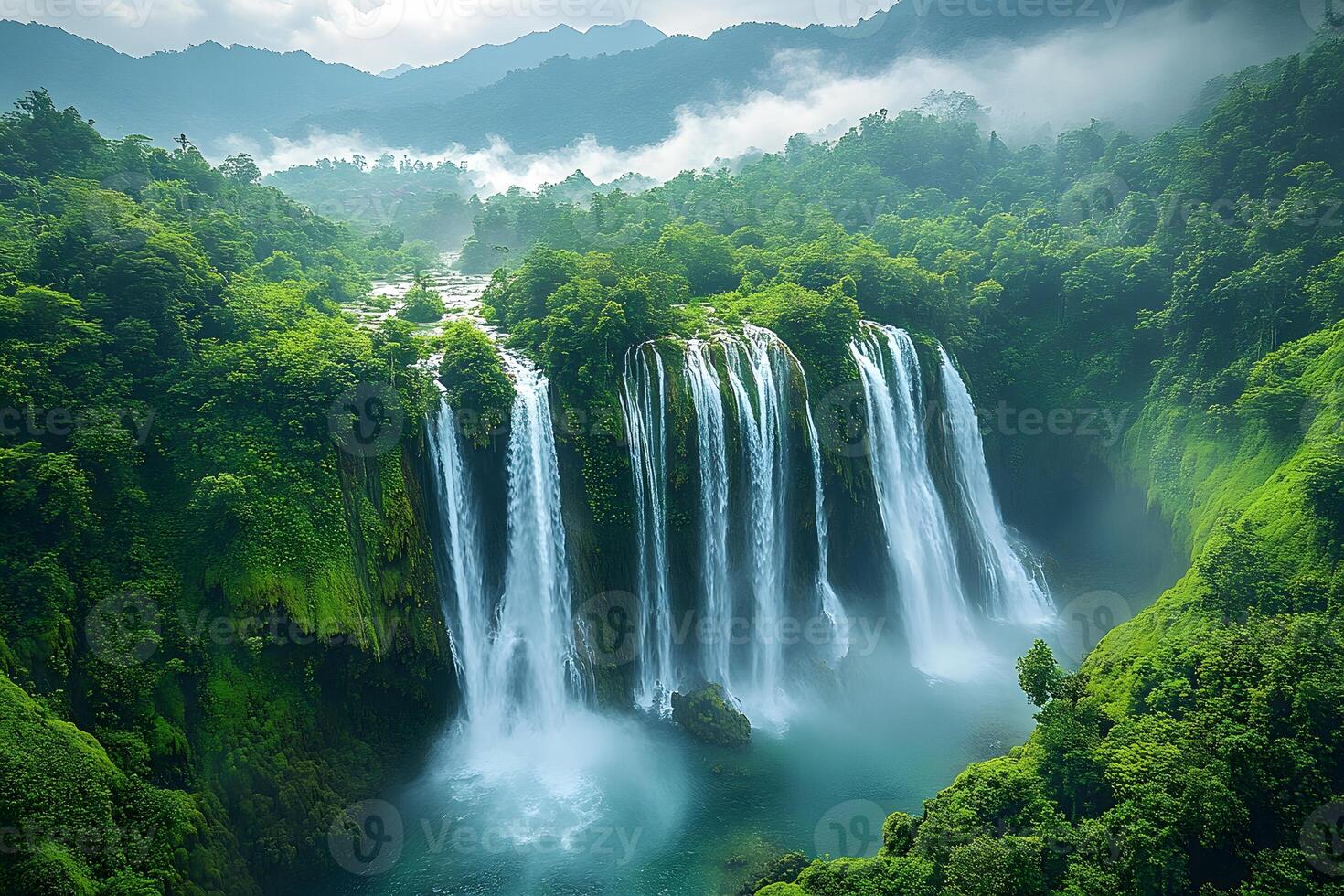 Majestic Waterfall in Lush Jungle Landscape Surrounded by Misty Mountains photo