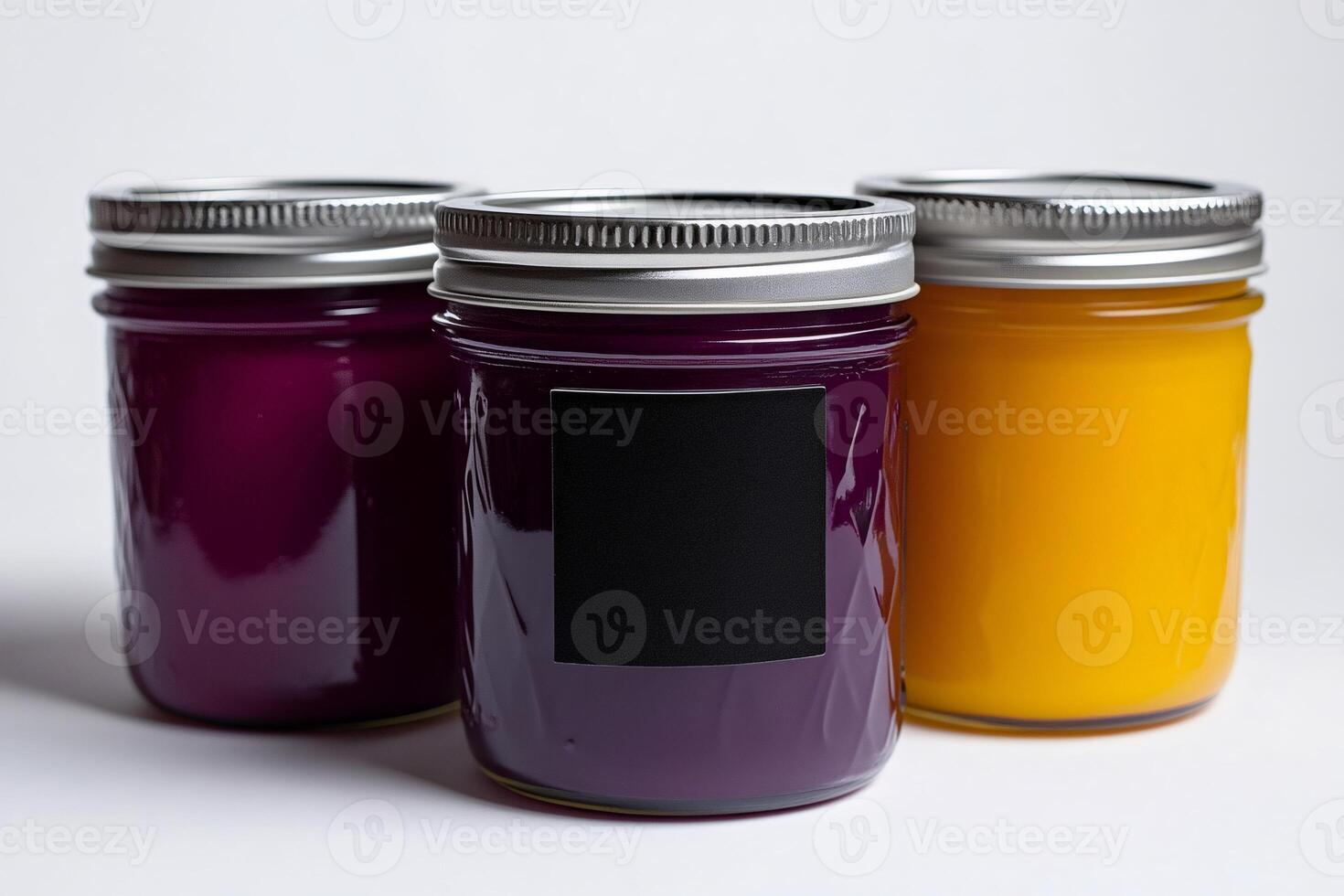 Three colorful glass jars with silver lids and blank label displaying vibrant jams or jellies photo