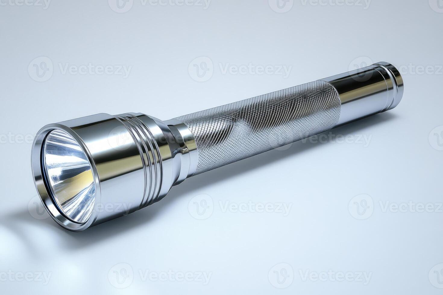 Chrome metal flashlight resting on white background photo