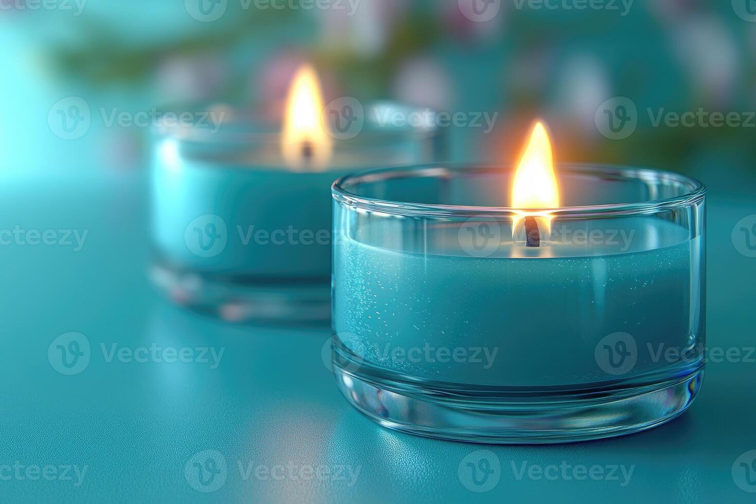 Two burning teal candles in glass holders on teal background create relaxing ambiance photo