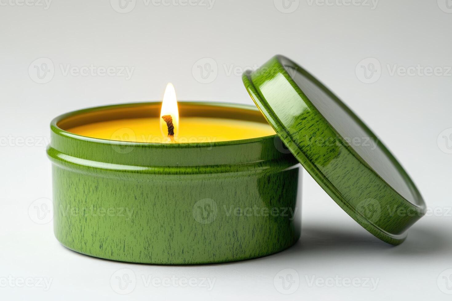 Burning beeswax candle in a green tin container with open lid photo