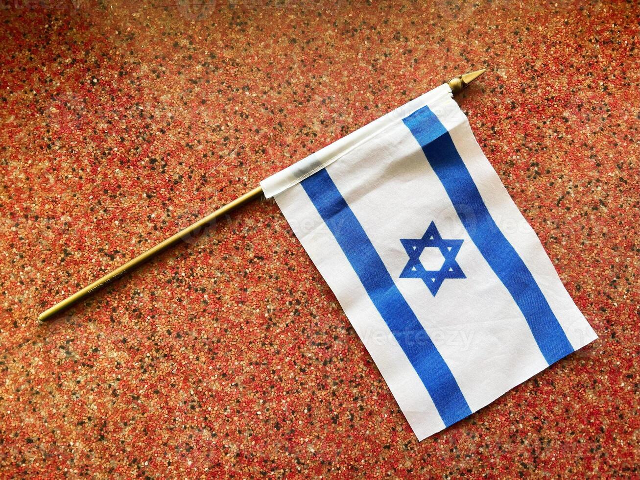 Israeli flag resting on speckled surface with golden pole photo