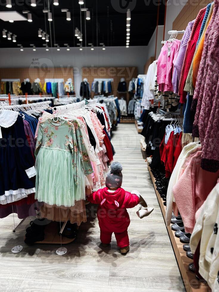 Child examining clothing racks in a colorful and vibrant apparel store photo