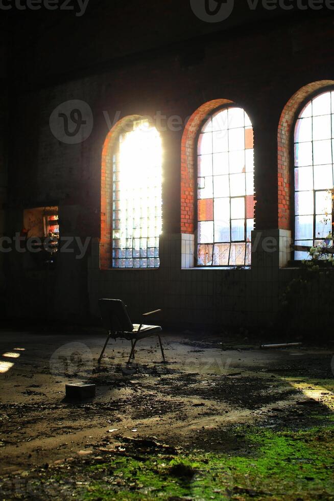 Spooky shot of chair in overgrown abandoned factory interior in backlight photo