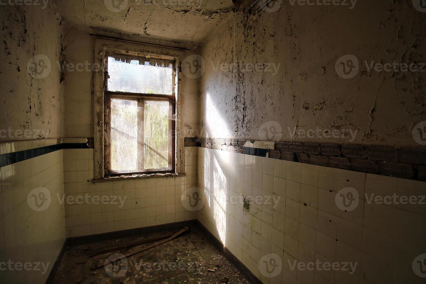 Desolate abandoned bathroom with sunlight shining through window photo