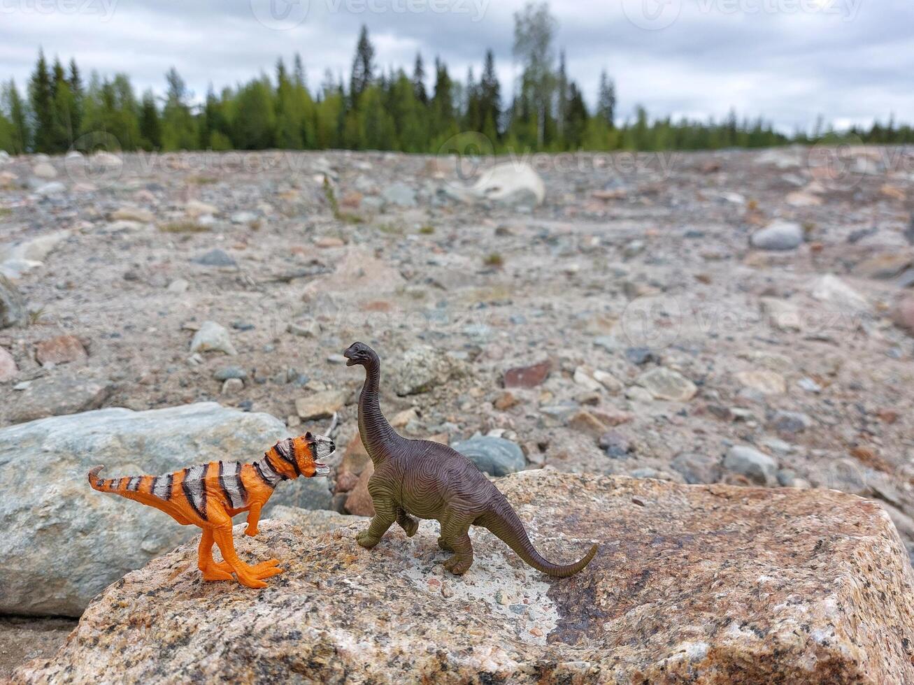 Two toy dinosaurs on rocks and debris photo
