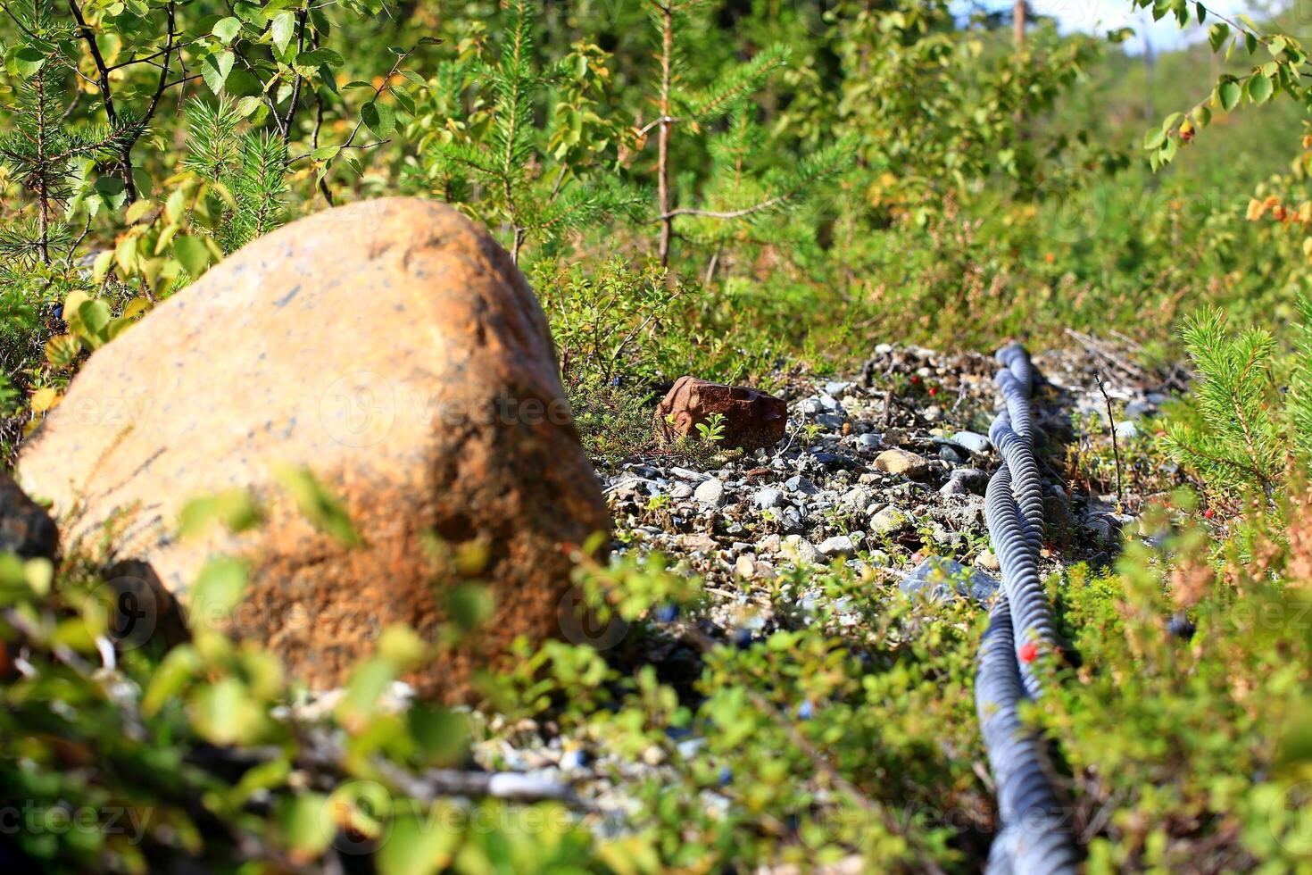 Pair of steel cables and boulder lying outside on the ground photo