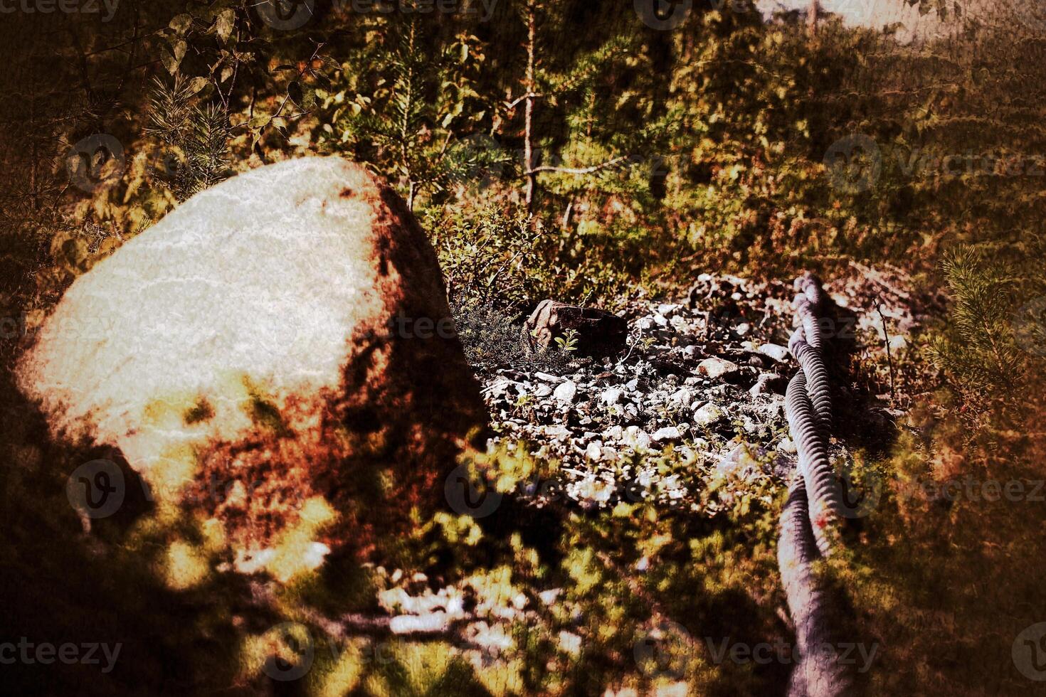 Grungy shot of pair of steel cables and boulder lying outside on the ground photo