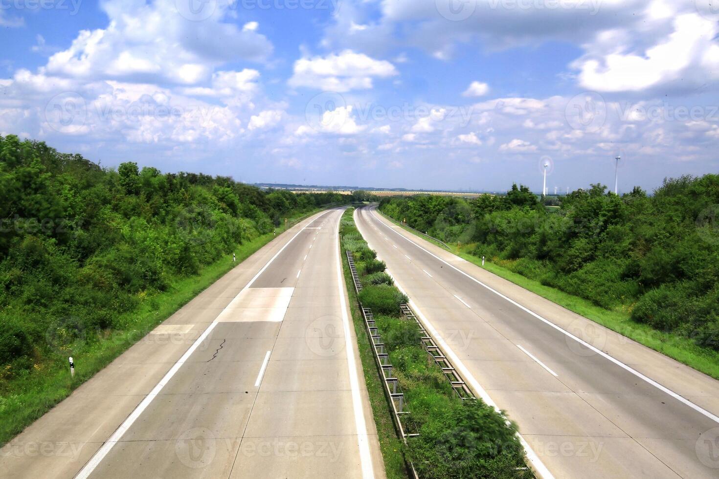 Empty German Autobahn surrounded by greenery and cloudy sky photo