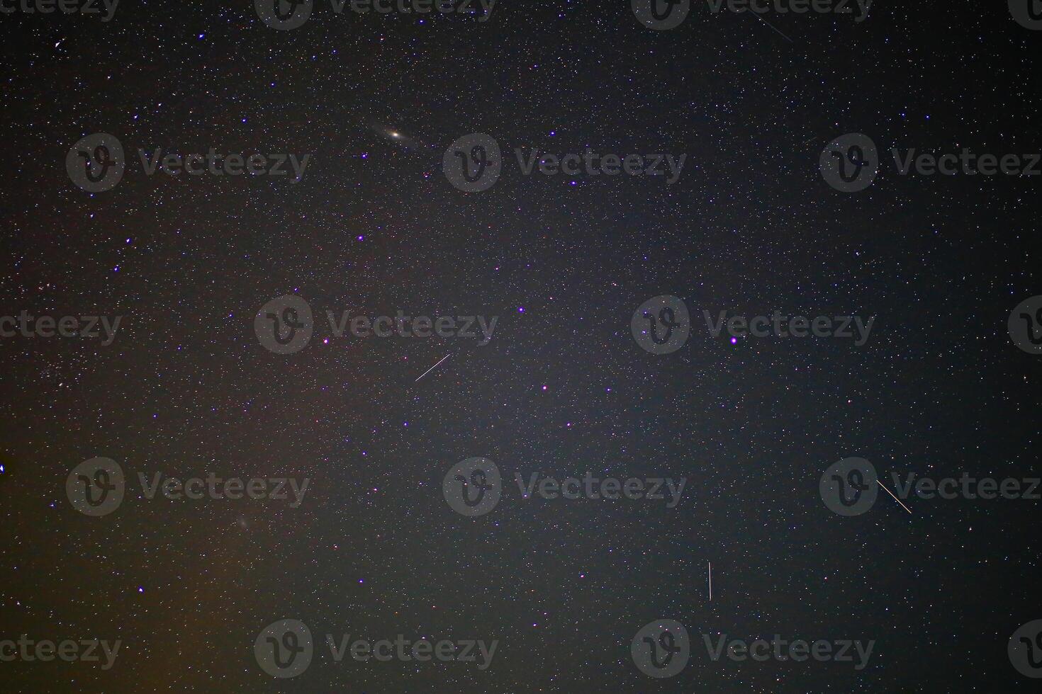 Stars and andromeda galaxy visible in a clear night sky with meteor streaks and distant constellations photo
