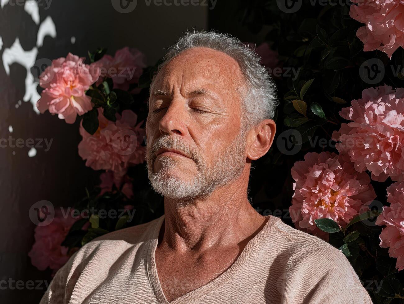 Senior man meditating peacefully in a garden filled with pink flowers photo