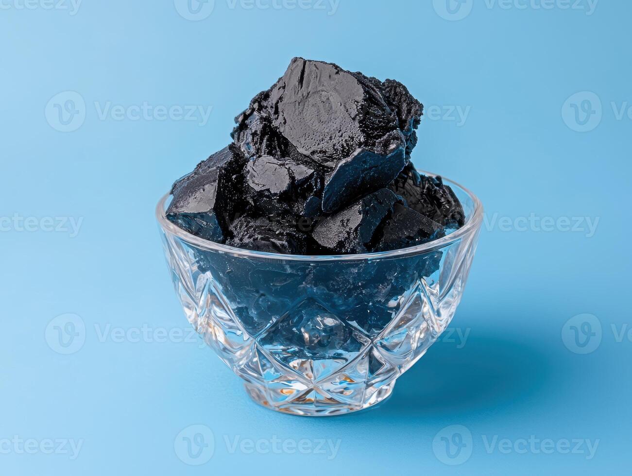 Black ice cream in a crystal bowl on a blue background photo