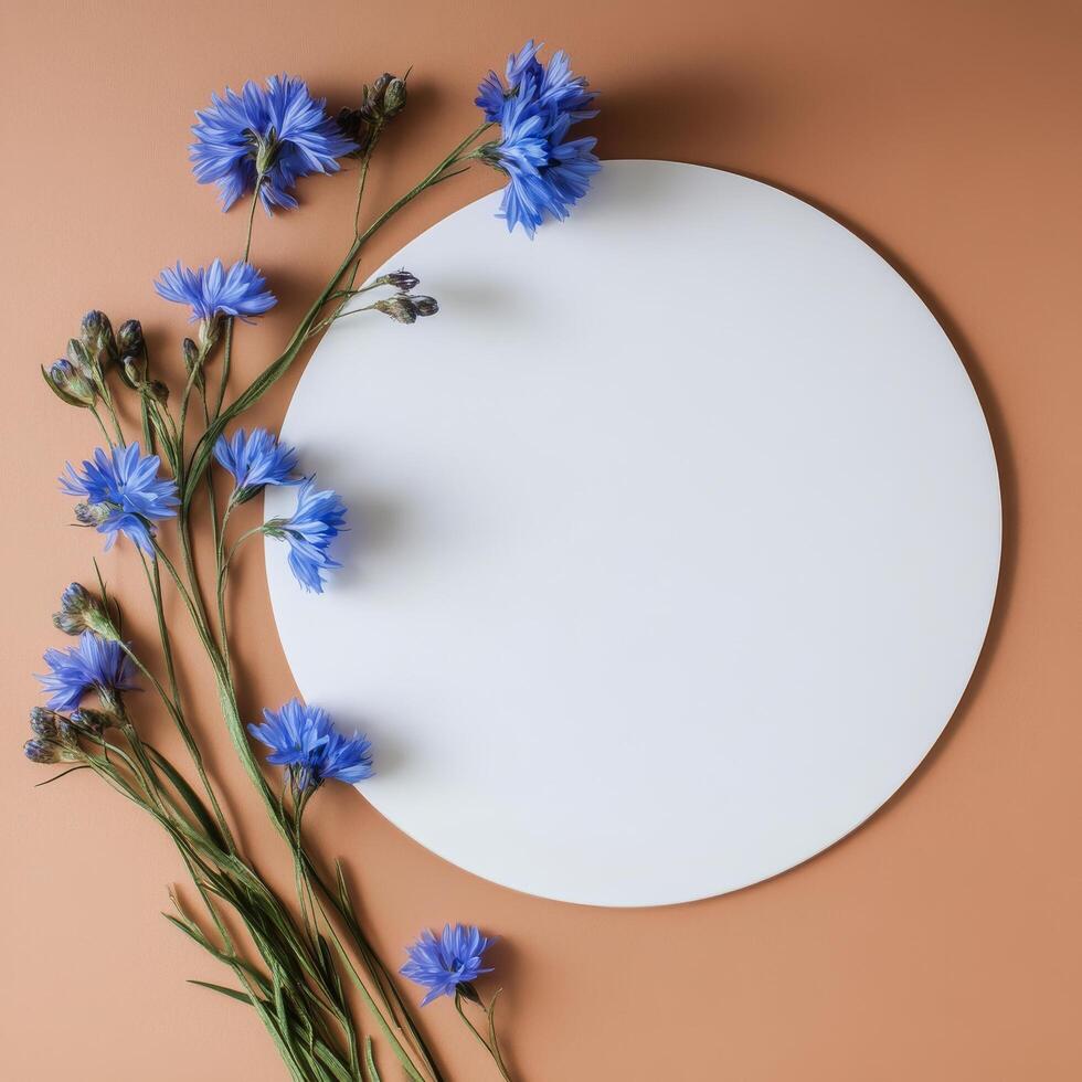 Blue flowers arranged around a white circle on a warm orange background photo